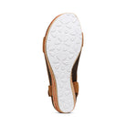 The image shows the bottom view of the Aetrex Womens Sydney Cognac sandal. It features a white rubber sole with floral patterns, a brown upper with cork-like edging, and built-in arch support for enhanced comfort.