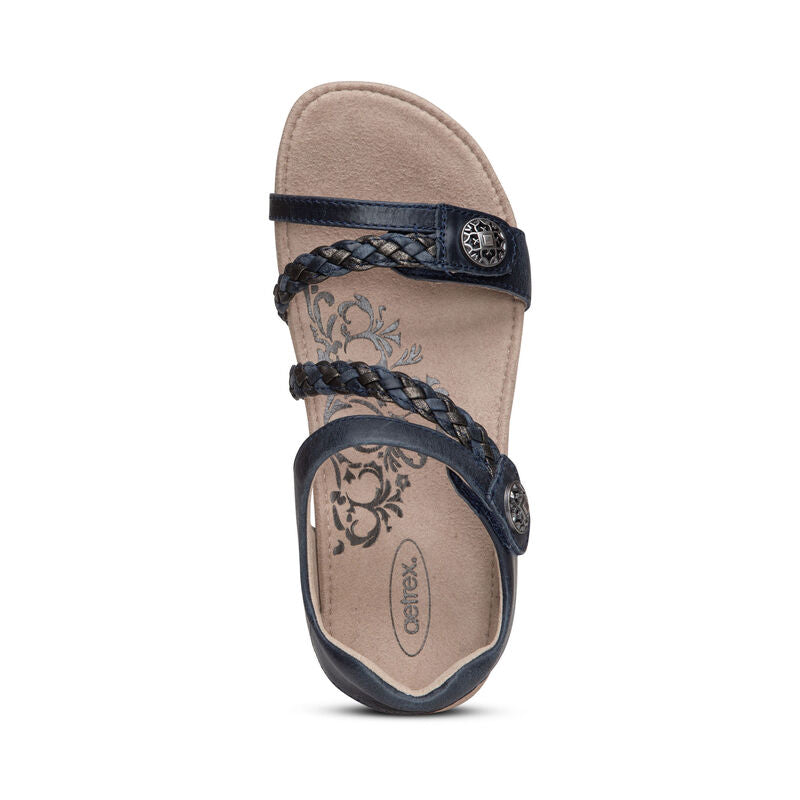 Top view of the Aetrex Womens Jillian Navy sandal, featuring braided straps, decorative metal buttons, a floral beige insole, and a Lynco orthotic footbed. Brand: Aetrex.