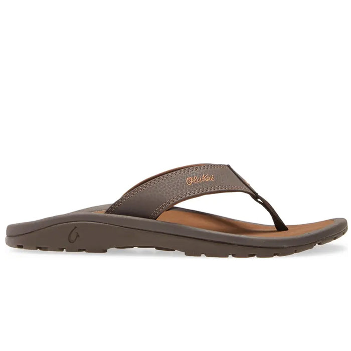 The OluKai Mens Ohana Dark Java Ray sandal features a water-resistant brown strap, tan anatomical footbed, slightly raised sole, and visible OluKai branding. Shown in side profile on a white background.