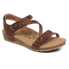 The Aetrex Womens Jillian Walnut sandal features a low wedge heel, walnut leather braided straps, metal buttons, adjustable fit, floral-patterned insole, and an orthotic footbed for comfort.