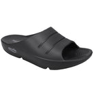 The Sovella Men’s PF Slide Black is a slip-on sandal with two raised stripes, a textured footbed, open toe, slight heel lift, and arch support for comfort recovery. Sovella branding is on the side of the sole near the heel.